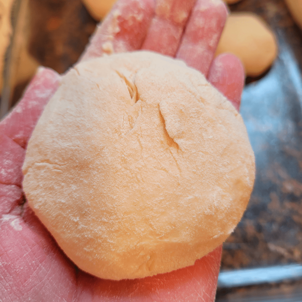 Image illustrates dough being shaped into dinner rolls.