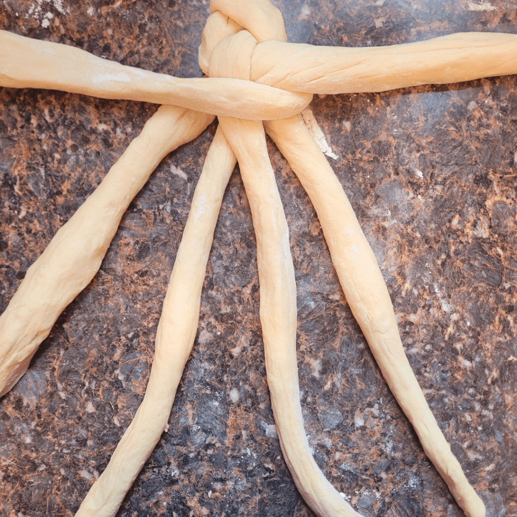 Image illustrates dough for a 6 braided challah bread recipe demonstrating how to braid a challah bread.