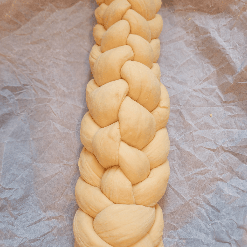 Image illustrates a 6 braided challah bread demonstrating how to braid a challah bread.