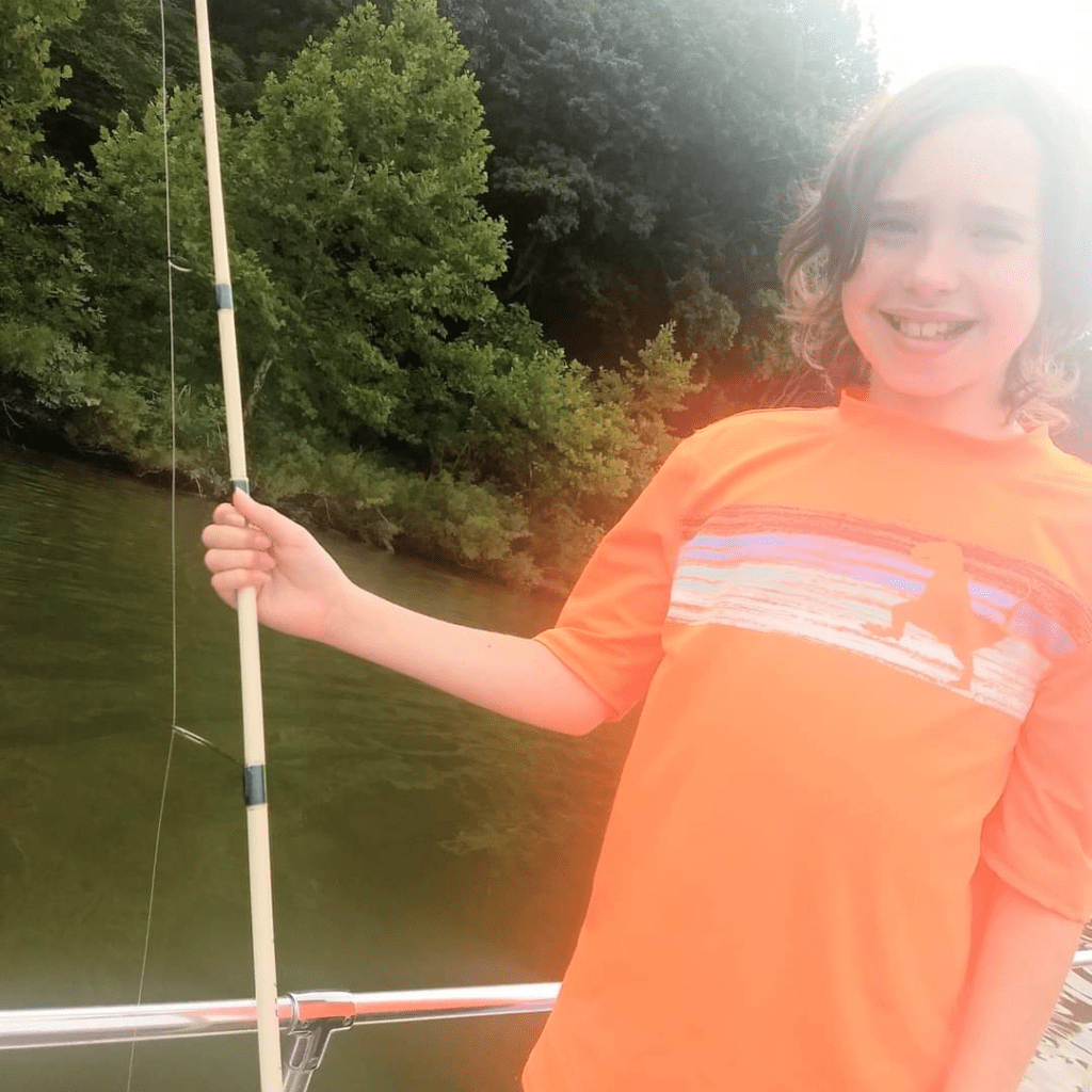 Image illustrates an image of a kid on a boat for lake fishing with kids.