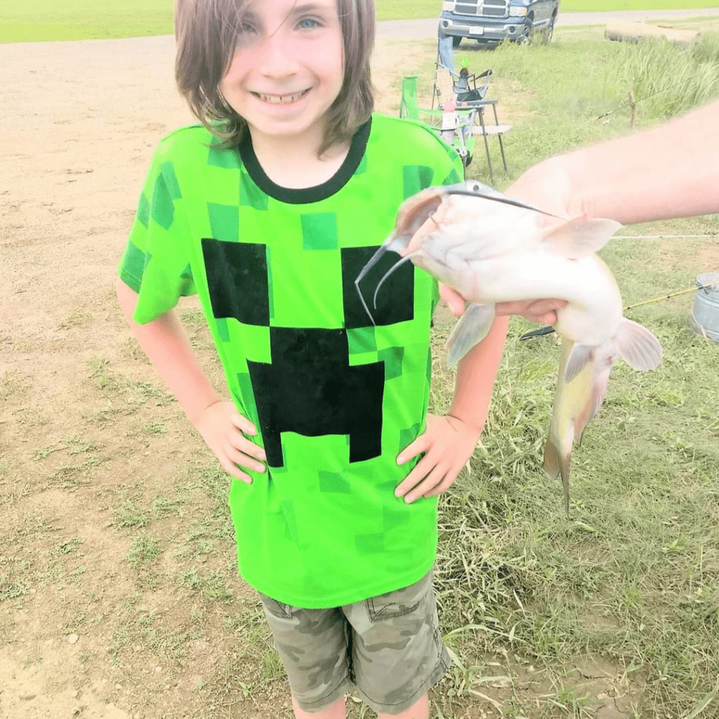 Image illustrates an image of a kid with a catfish.