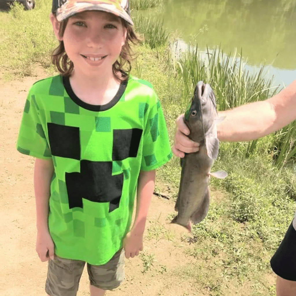 Image illustrates an image of a kid with a catfish.