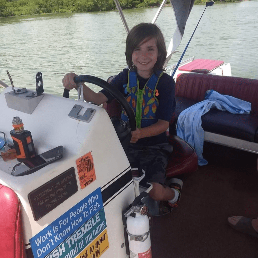 Image illustrates an image of a kid driving a boat for lake fishing with kids.