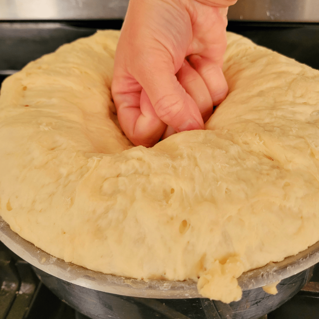 Image illustrates proofed dough being punched down for a one hour dinner rolls recipe.