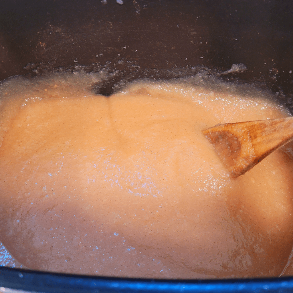 Image illustrates blended cooked pears in a slow cooker for canning pear sauce.