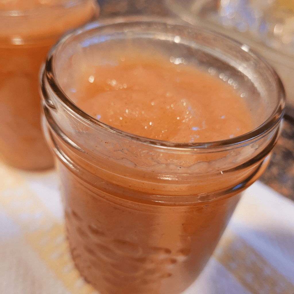 Image illustrates jars filled with pear sauce for a canning pear sauce recipe.