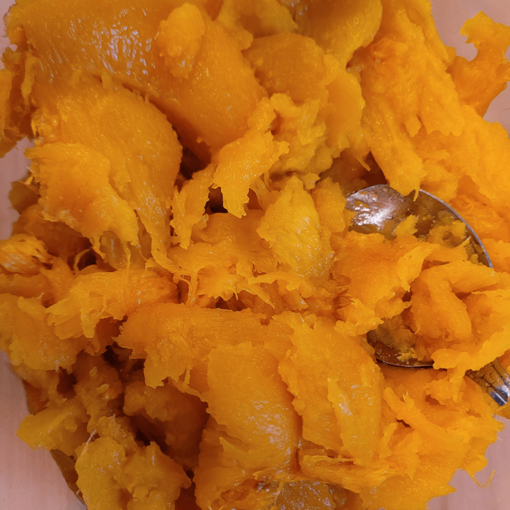 Image illustrates a sugar pumpkin scooped out for a pumpkin bread recipe.