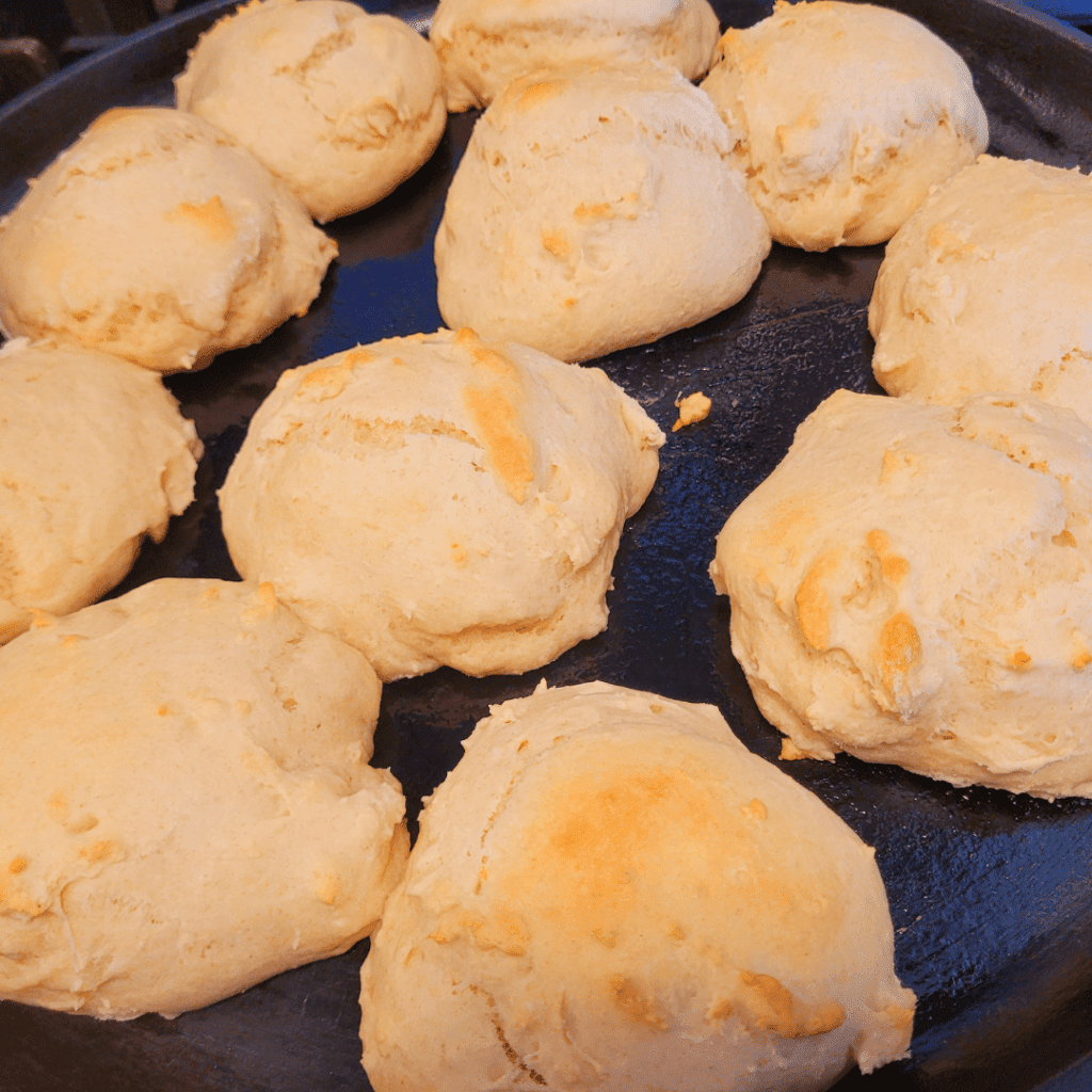 Image illustrates baked biscuits on a cast iron baking pan.
