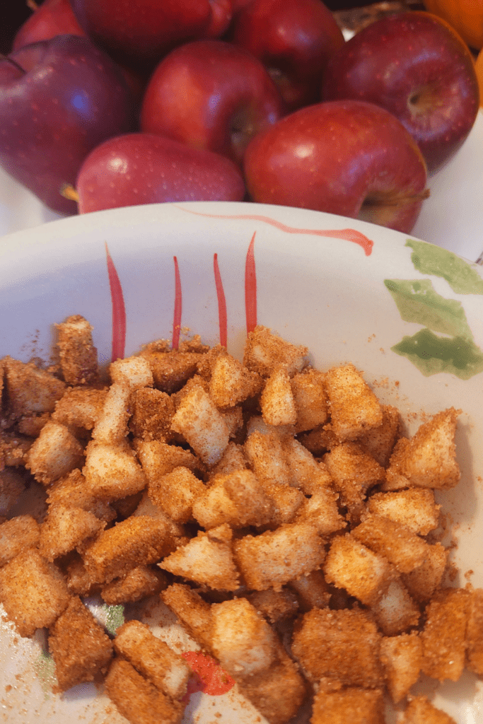 Image illustrates diced apples covered in cinnamon and sugar for an apple fritter bread recipe. 