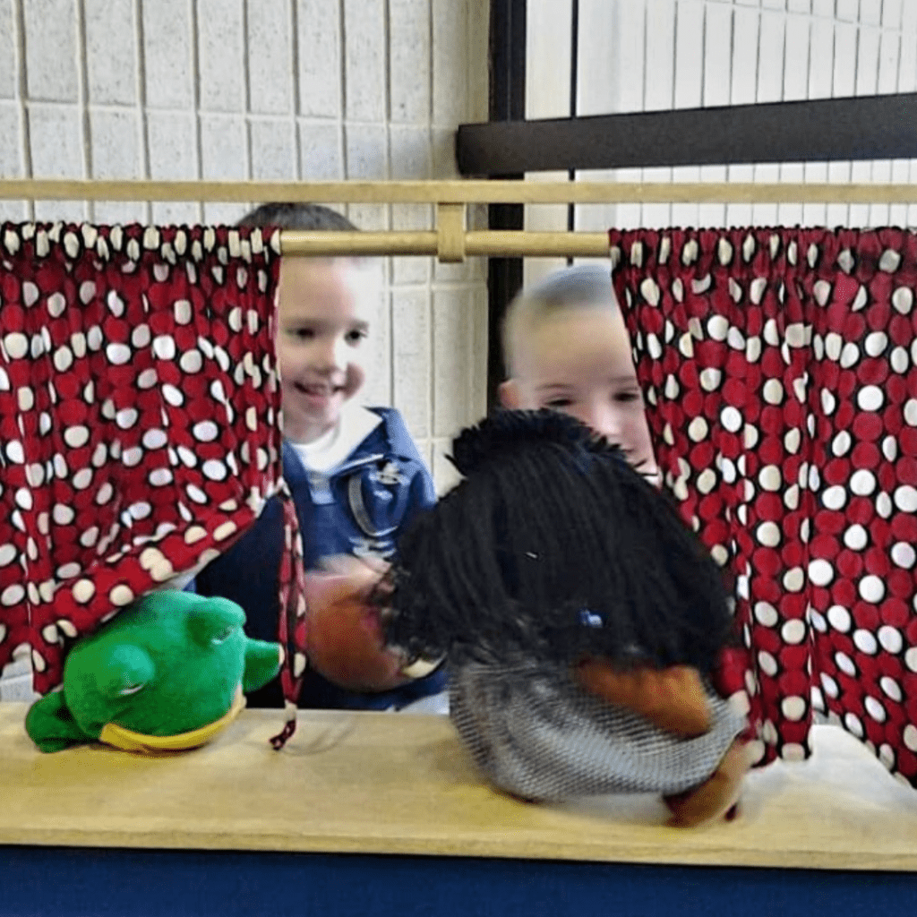 Image illustrates kids playing in a library puppet theater. 