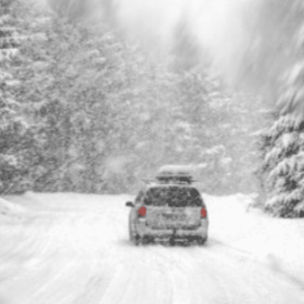 Image illustrates a car driving in a winter storm.