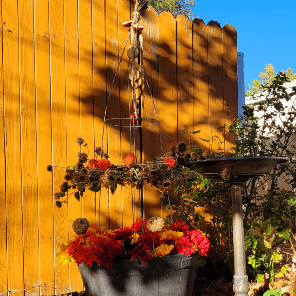 Image illustrates a bird feeder obelisk garden with a bird bath.