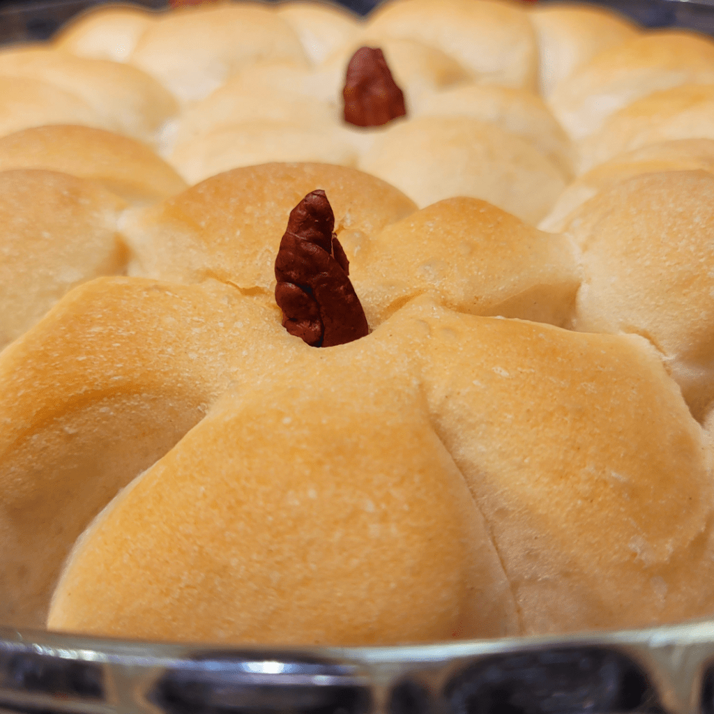 Image illustrates pumpkin-shaped rolls with pecan stem presented with a breaded cornucopia. 