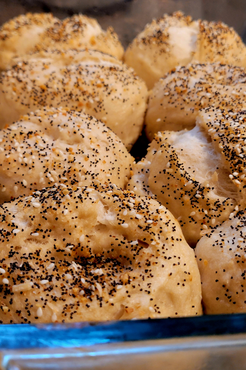 Image illustrates baked bagels with various toppings demonstrating information on how to make sourdough bagels. 