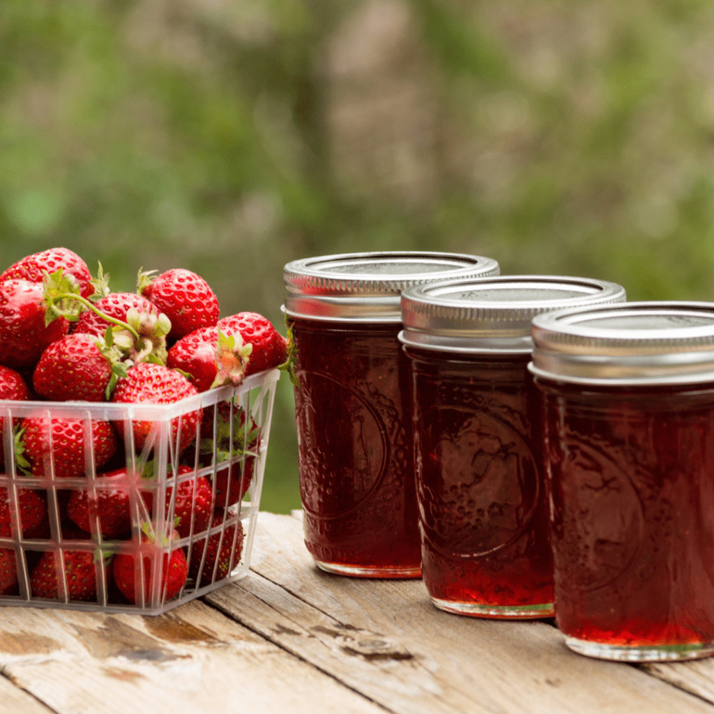 Image illustrates jars of jam and fresh strawberries demonstration a strawberry shortcake jam recipe. 