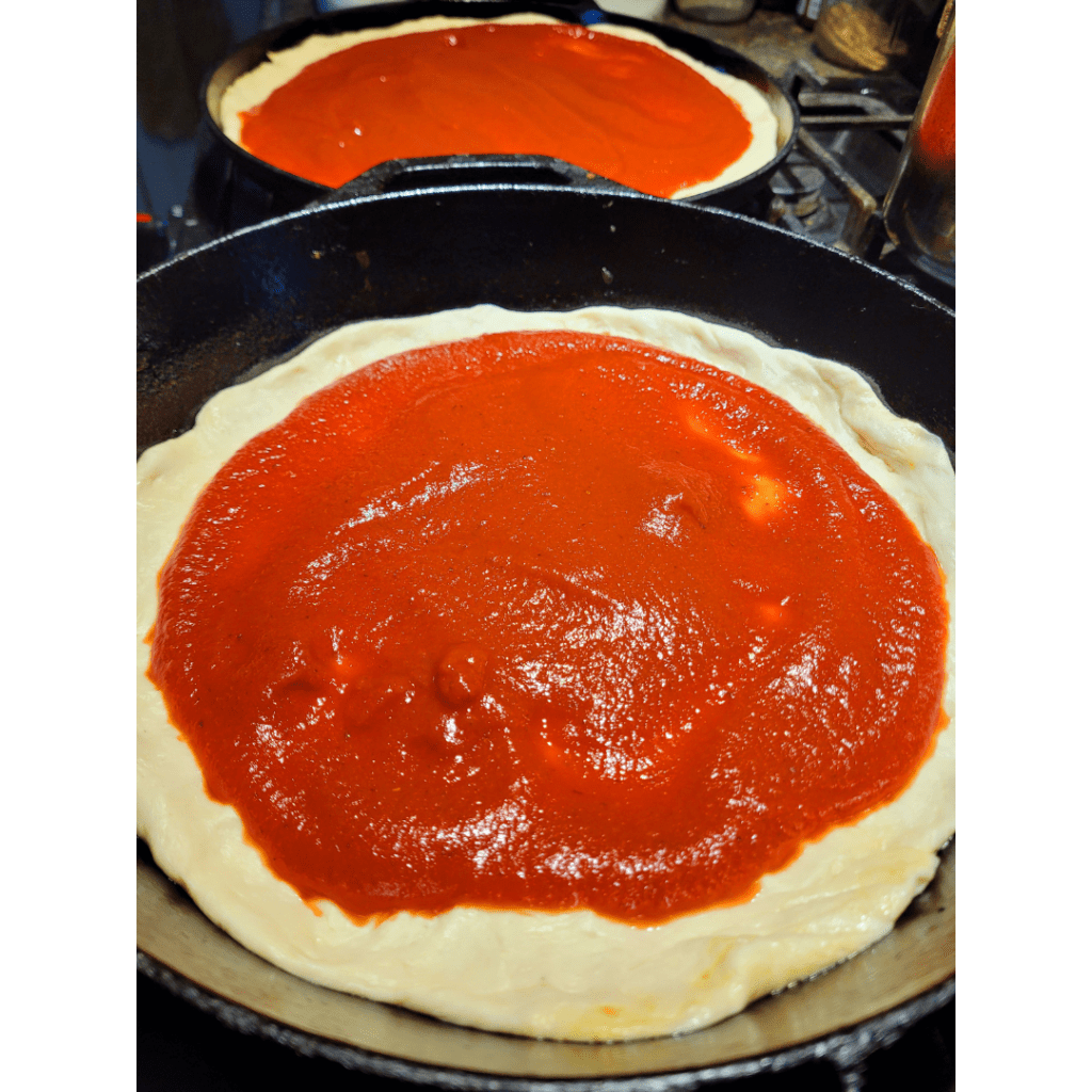 Image illustrates sourdough pizza dough on cast iron pans. 