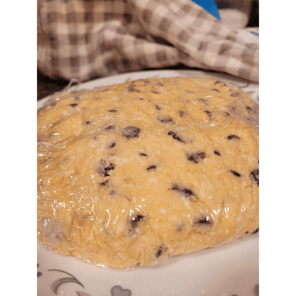 Image illustrates sourdough discard scones wrapped in plastic wrap. 