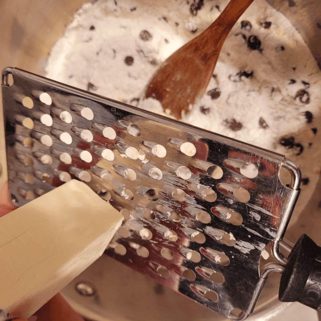 Image illustrates butter being grated in a mixture for sourdough discard scones. 