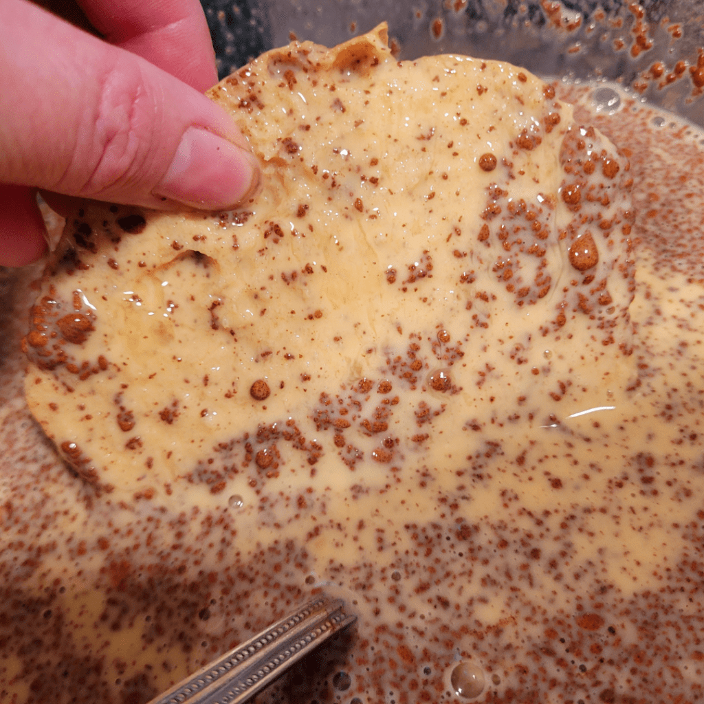 Image illustrates bread soaking in egg mixture for sourdough French toast. 
