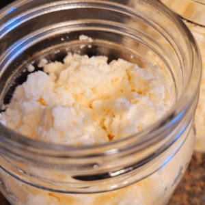 Image illustrates ricotta cheese in a a Mason jar demonstrating an easy homemade ricotta cheese recipe.