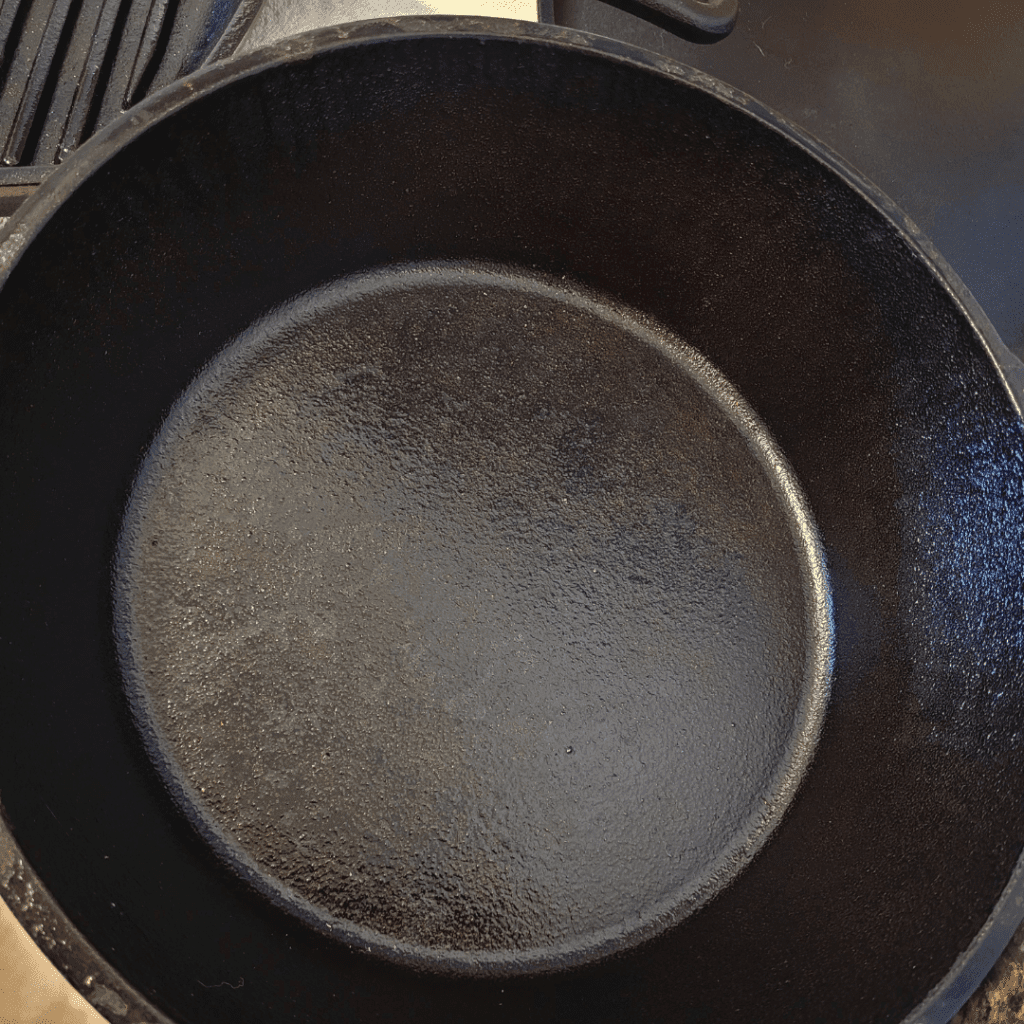 Image illustrates a seasoned cast iron pan demonstrating how to season cast iron for cooking. 