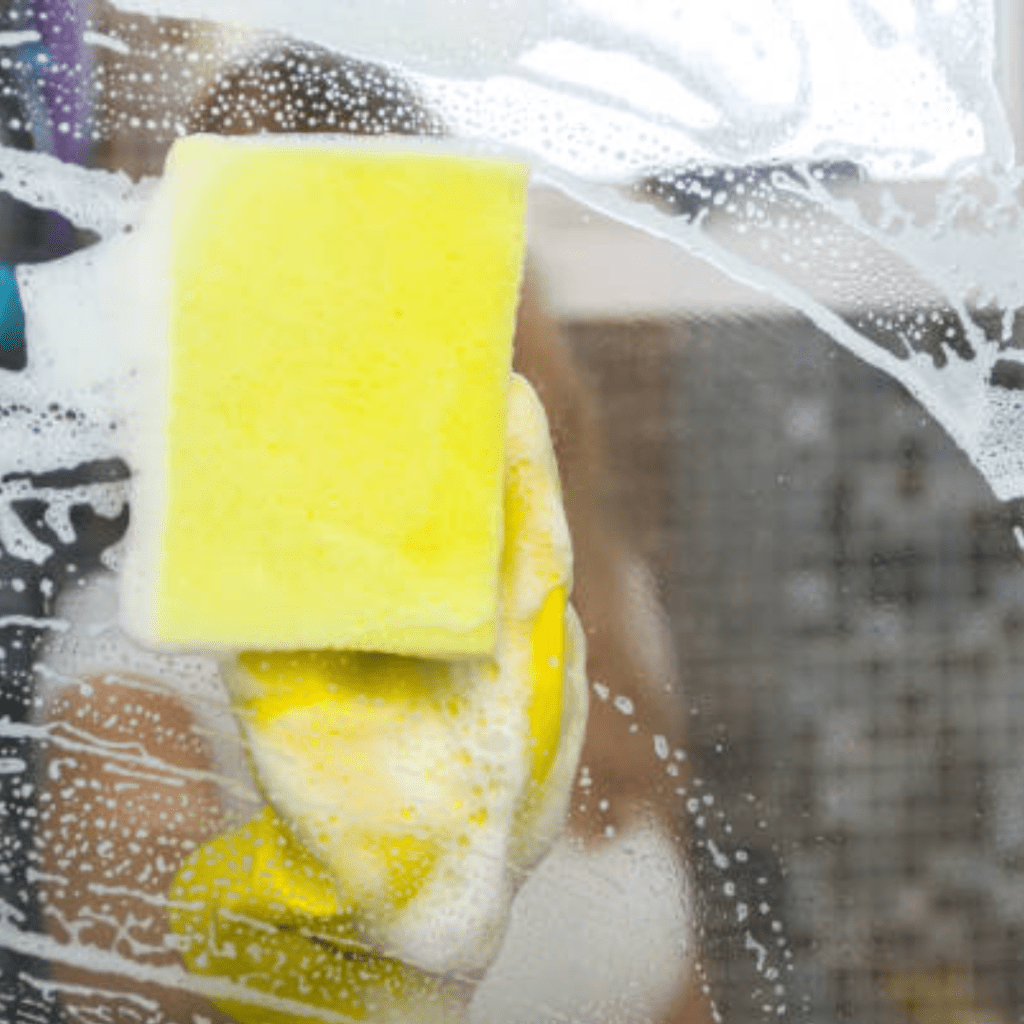 Image illustrates a person cleaning a shower.