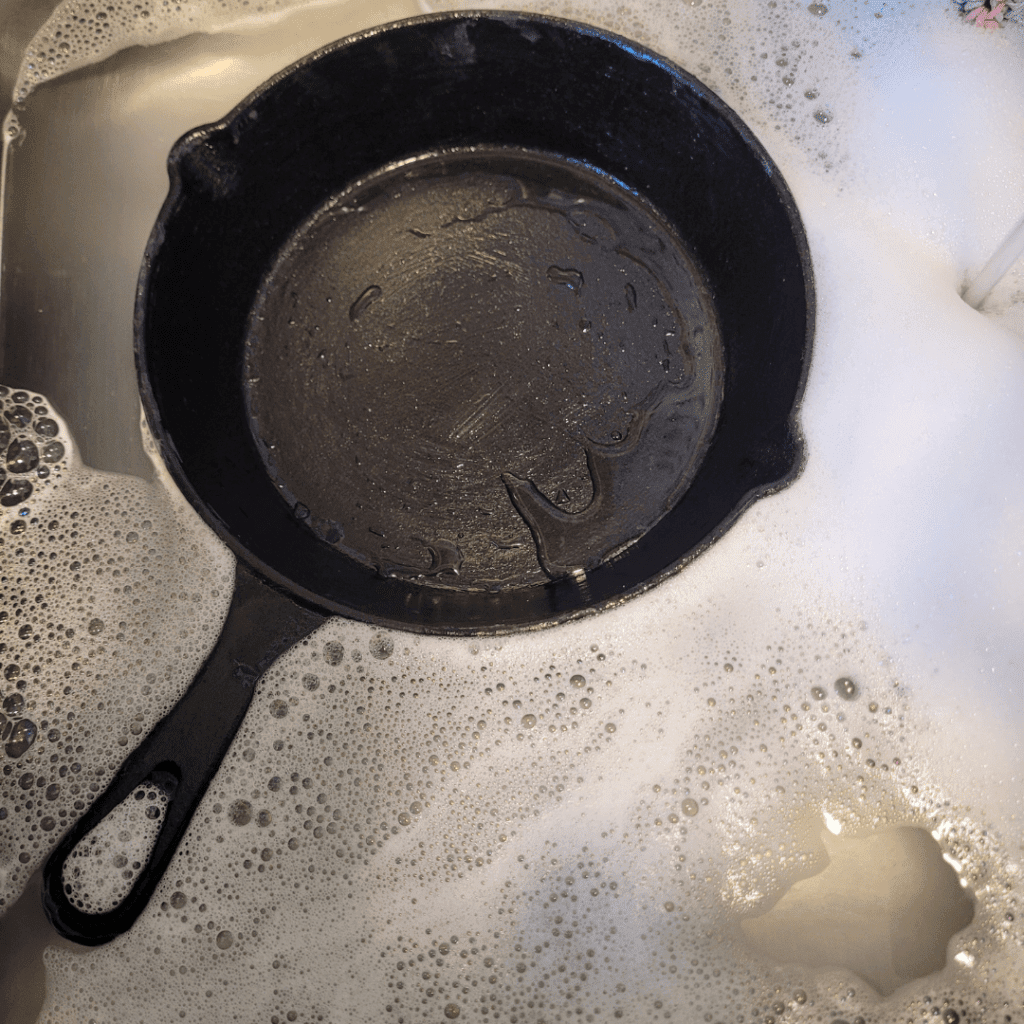 Image illustrates a cast iron pan being cleaned demonstrating how to season cast iron for cooking. 