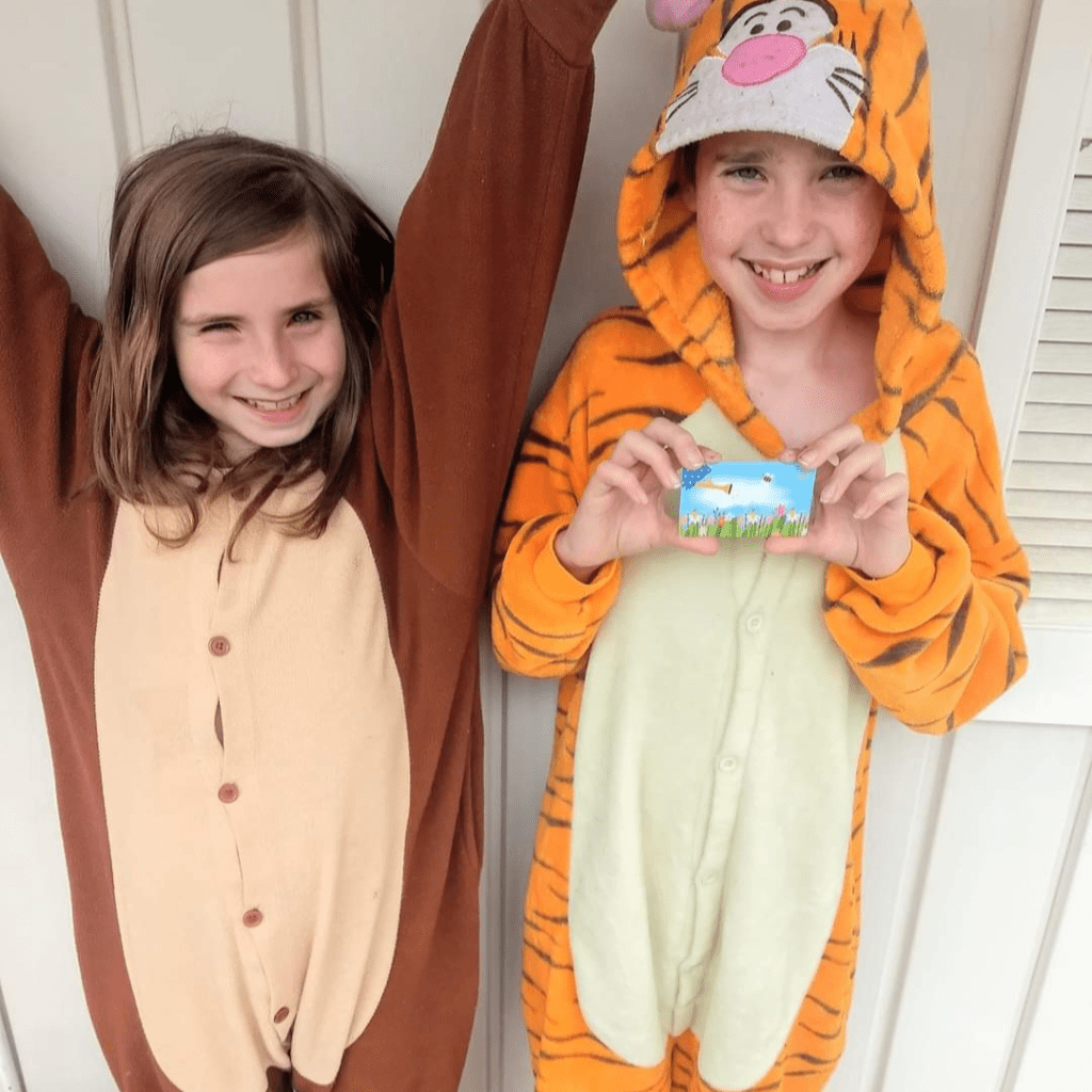 Image reveals two young kids holding a gift card. 