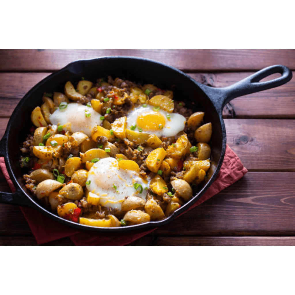 Image illustrates breakfast being cooked on a cast iron skillet. 