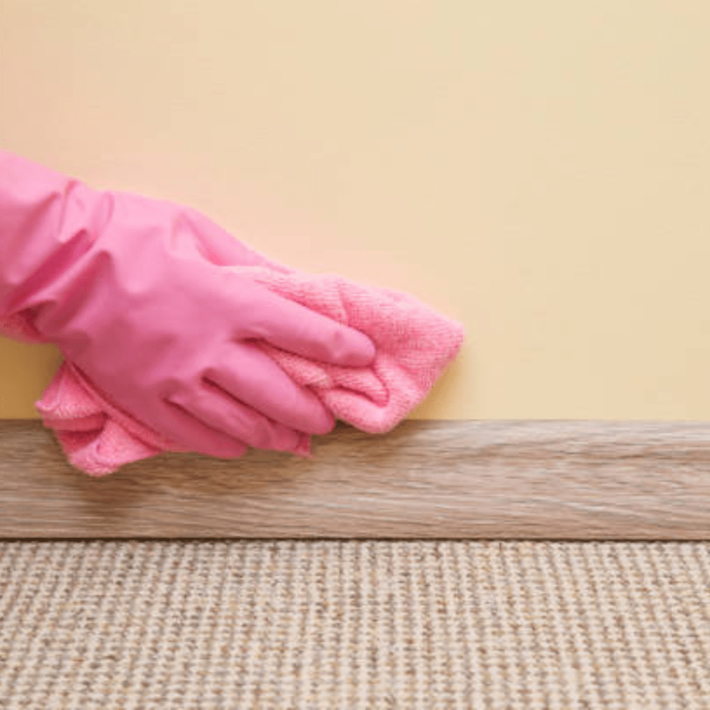 Image illustrates a person cleaning baseboards for spring cleaning. 