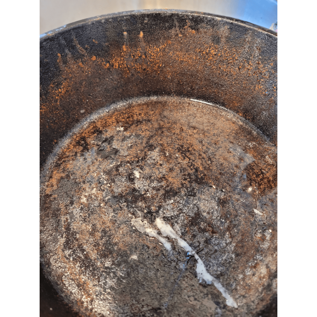 Image illustrates a rusty cast iron pan demonstrating how to season cast iron for cooking. 