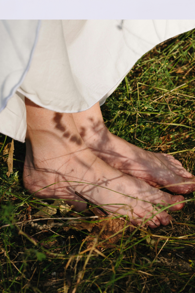 Image illustrates barefoot in grass for barefoot grounding.