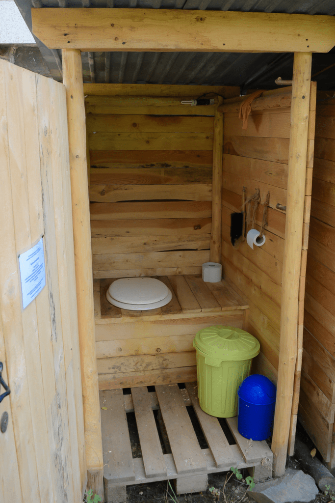 Image illustrates an outhouse with composting toilet systems.