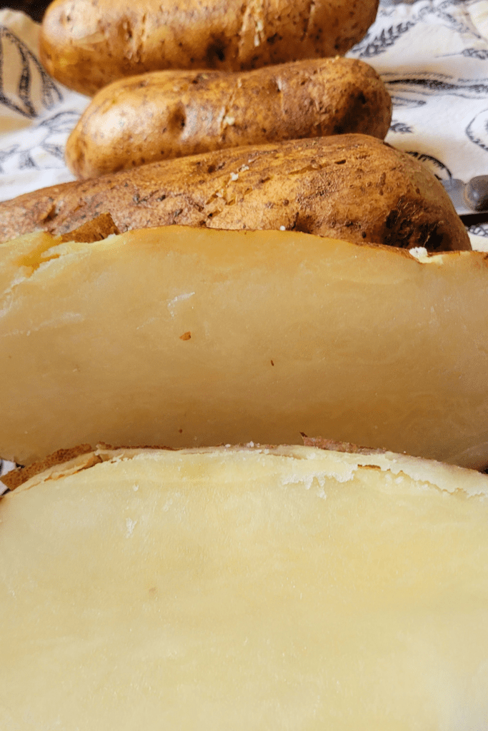 Image illustrates potatoes cut in half for twice baked potatoes casserole.