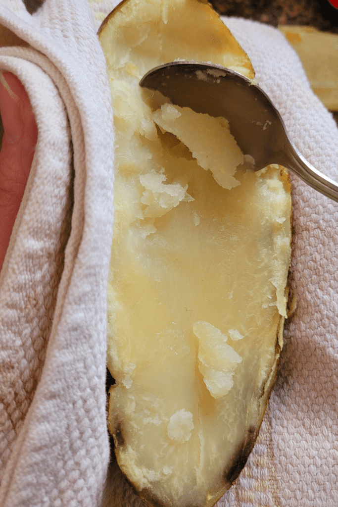 Image illustrates scooping out the flesh of potatoes for twice baked potatoes casserole.