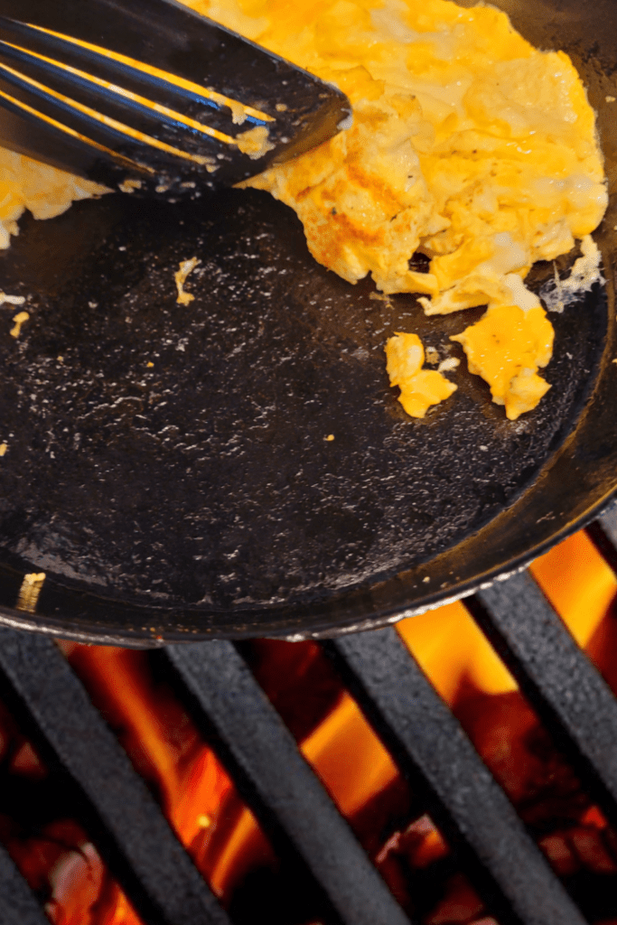 Image illustrates scrambled eggs in a cast iron skillet.
