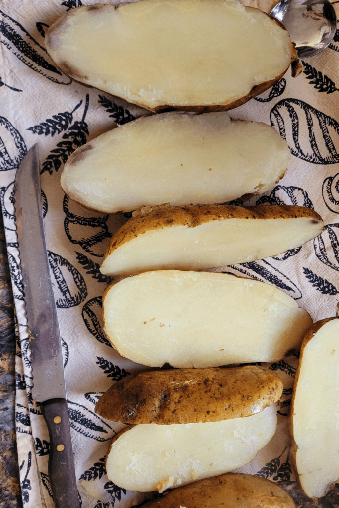 Image illustrates potatoes cut in half for twice baked potatoes casserole.
