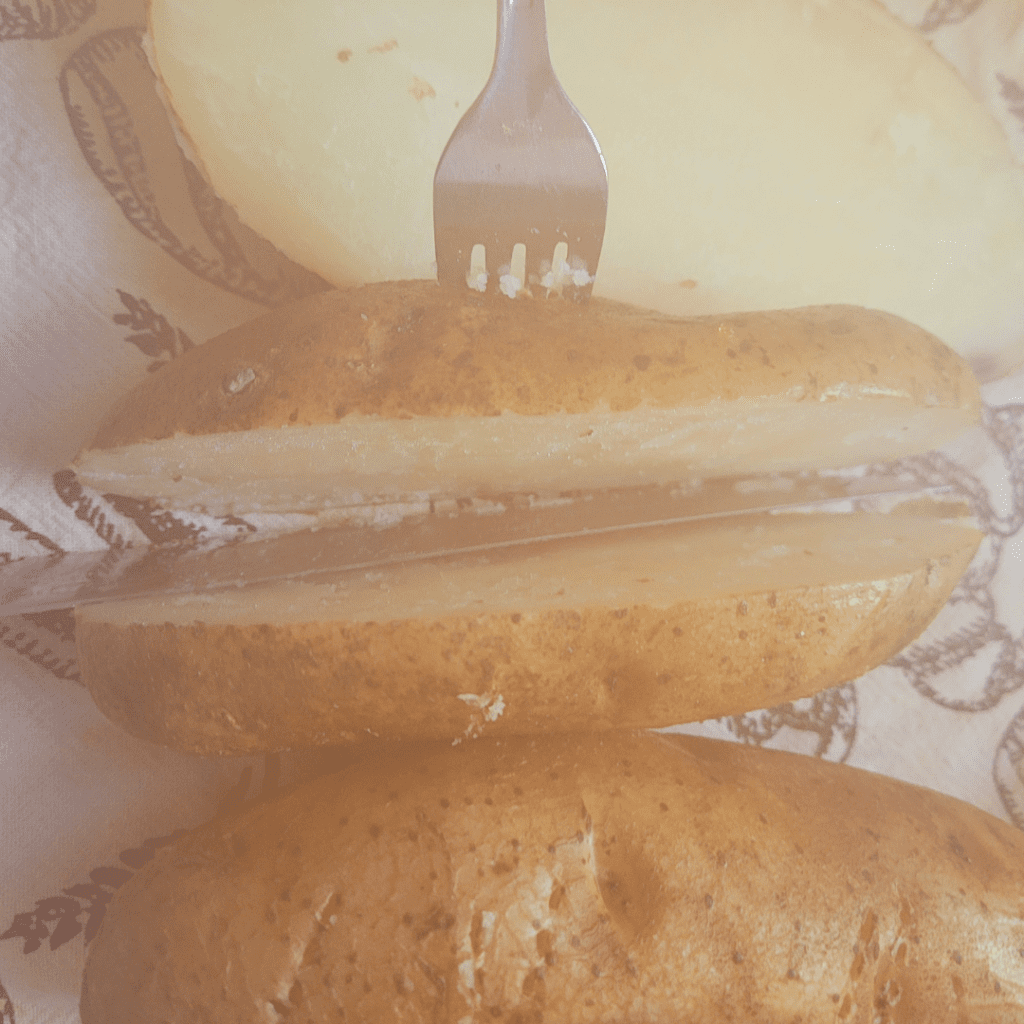 Image illustrates slicing a potato in half for twice baked potatoes casserole.