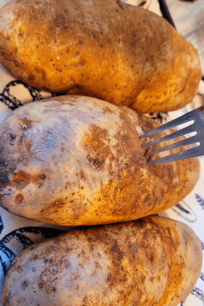 Image illustrates poking potatoes with a fork for twice baked potatoes casserole.