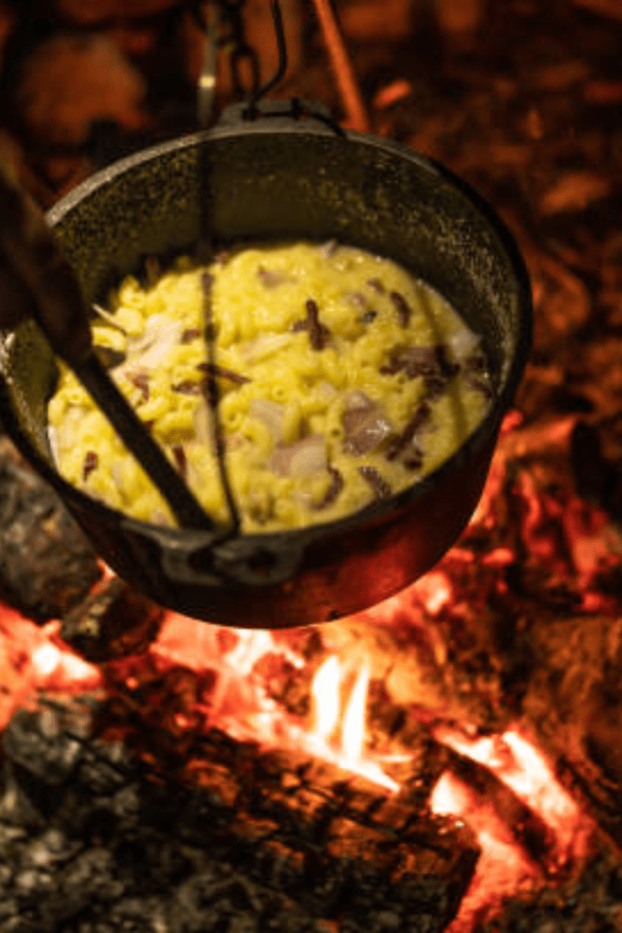 Image illustrates a survival cooking set over a fire. 