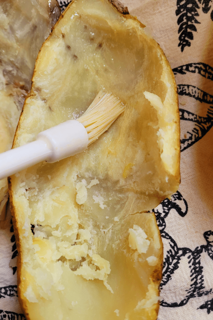 Image illustrates brushing butter on potato boats for twice baked potatoes casserole.