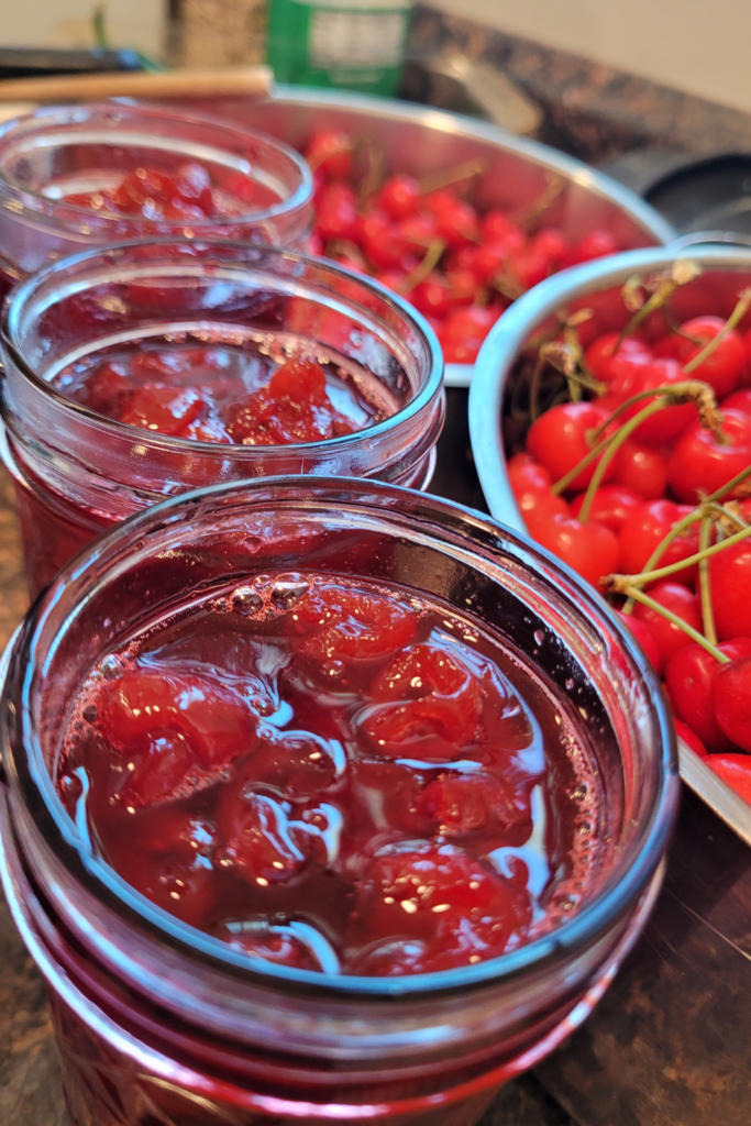 Image illustrates canning whole cherries.