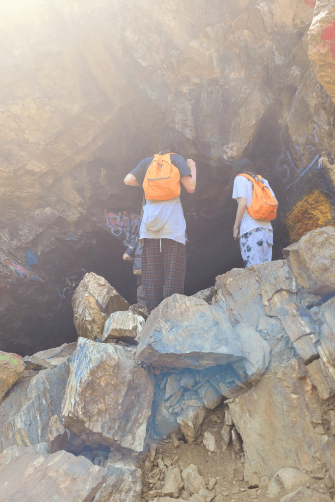 Image illustrates hikers in a cave in a canyon.