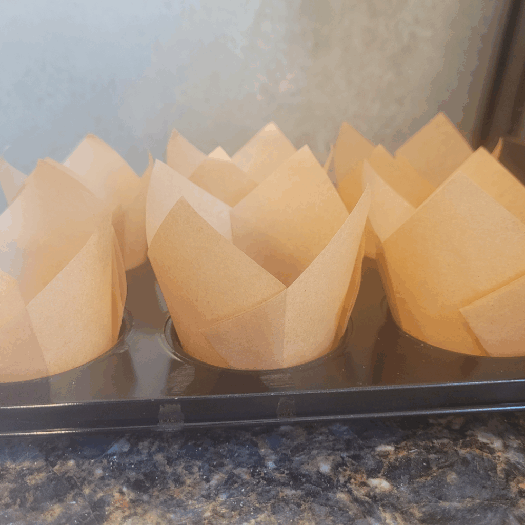 Image illustrates sourdough banana muffins in tulip-style muffin liners.