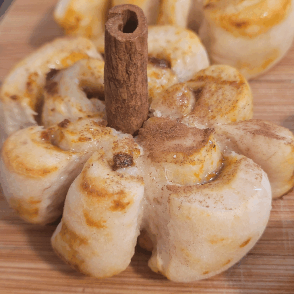 Image illustrates sourdough pumpkin shaped cinnamon rolls.