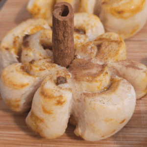 Image illustrates sourdough pumpkin shaped cinnamon rolls.