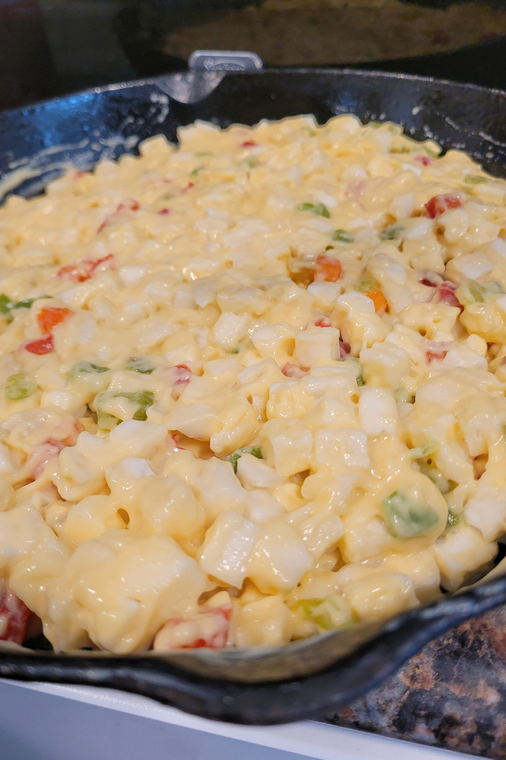 Image illustrates cheese potato casserole in a cast-iron skillet.