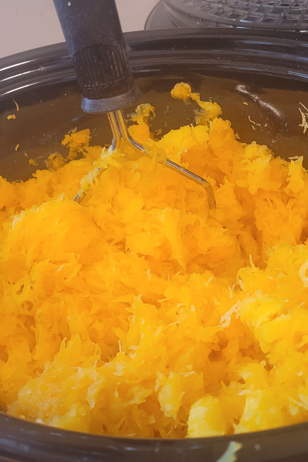 Image illustrates cooked down butternut squash in a crockpot for butternut squash butter.