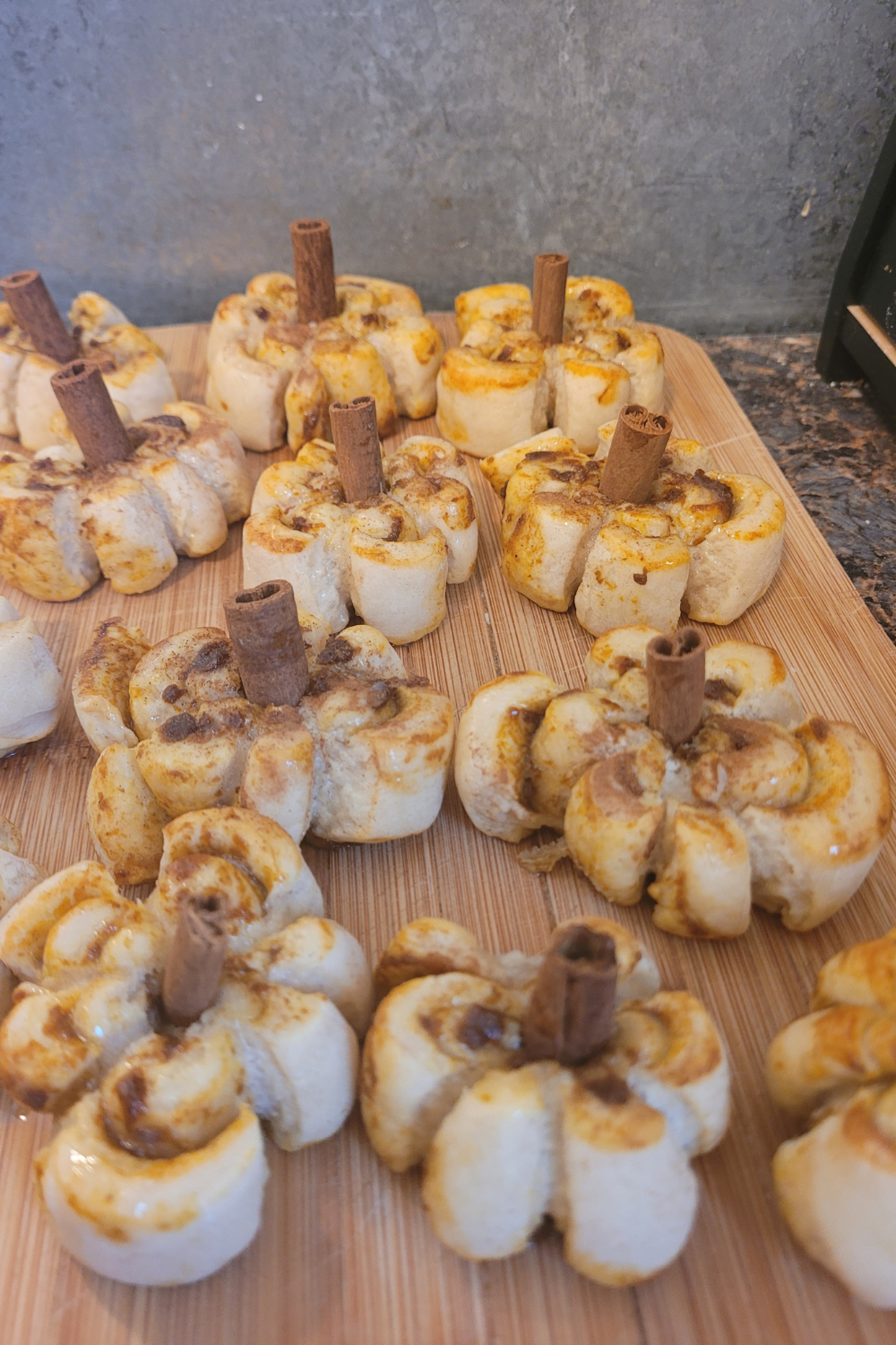 Image illustrates sourdough pumpkin shaped cinnamon rolls.