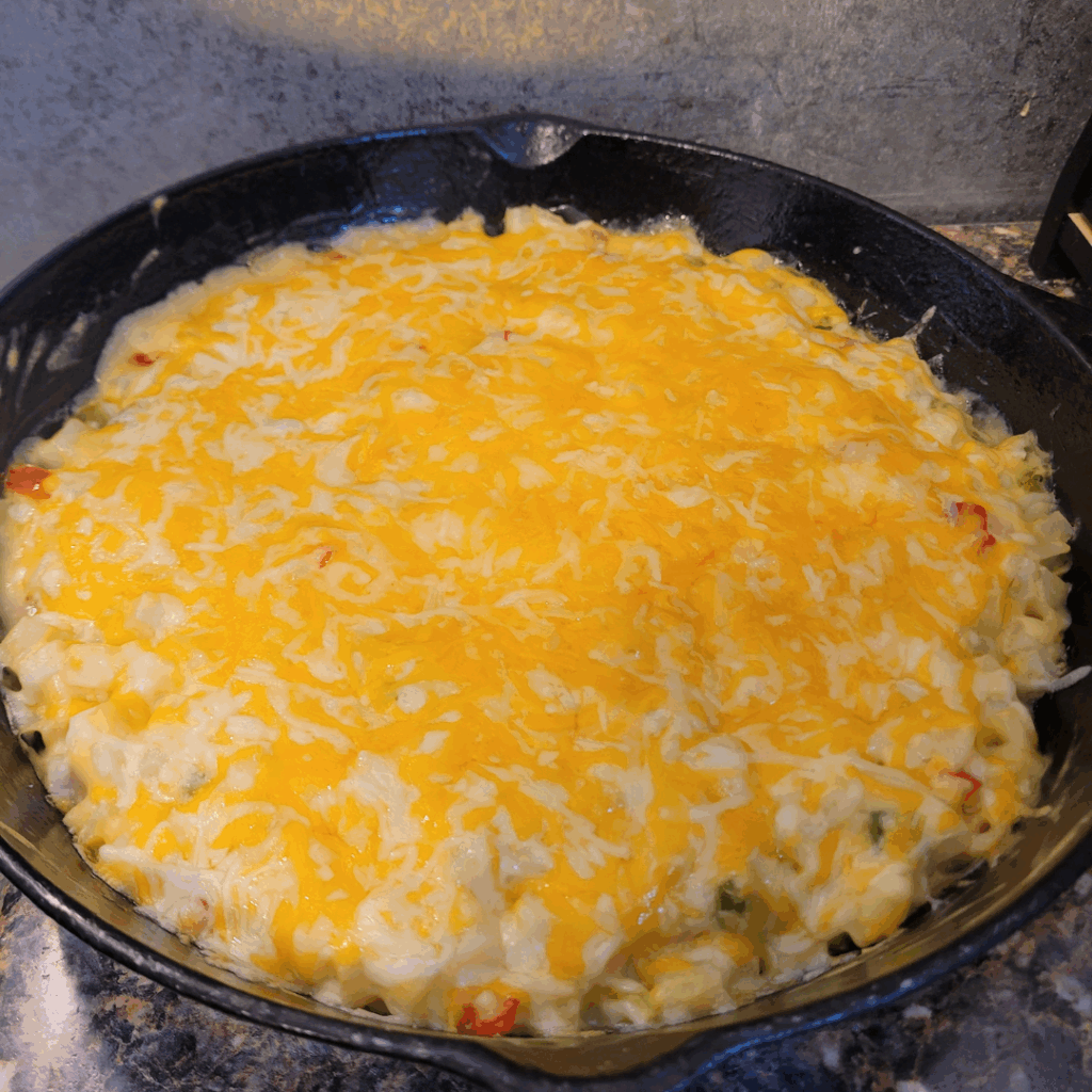Image illustrates cheese potato casserole in a cast-iron skillet.